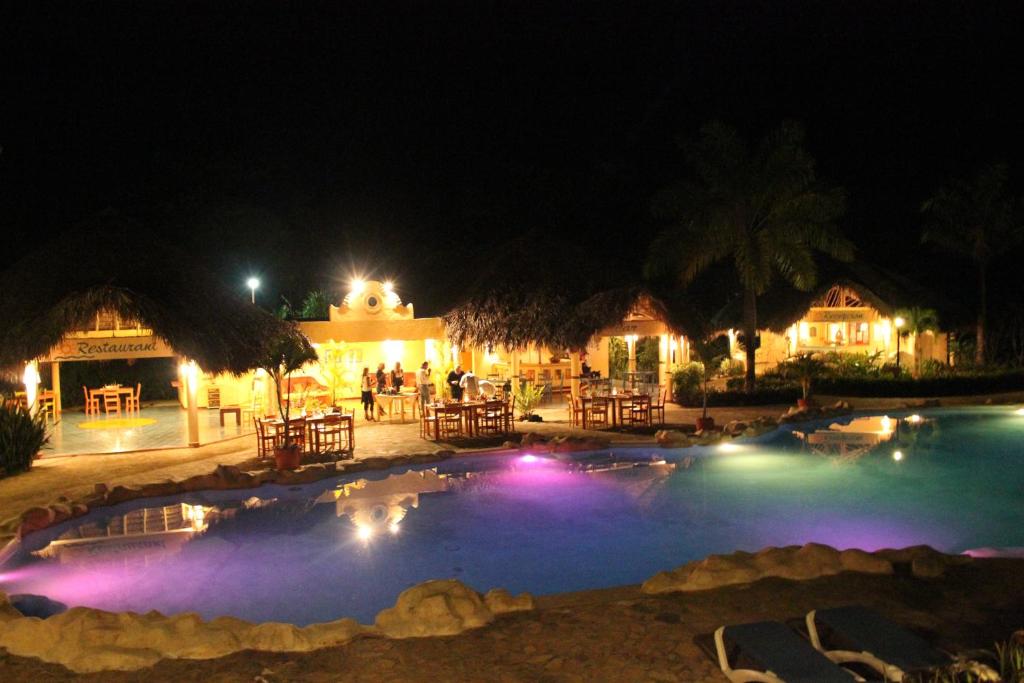a large swimming pool at night with people standing around it at Hotel - Residencial Madrugada in Las Terrenas