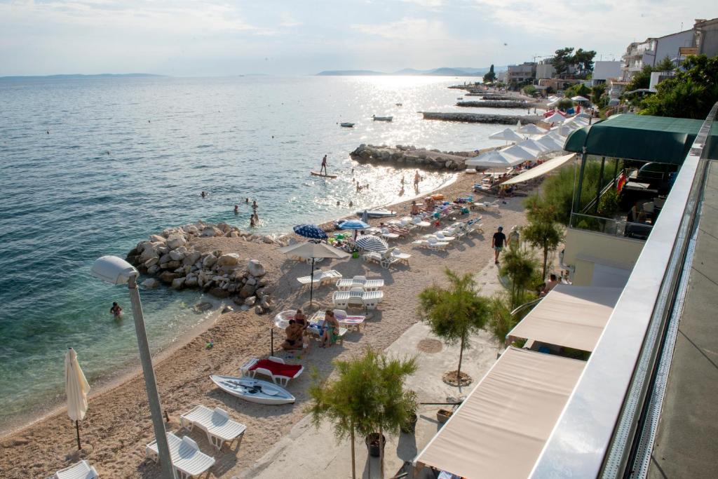 a beach with chairs and umbrellas and people on it at Apartments Zanic on The Beach in Podstrana