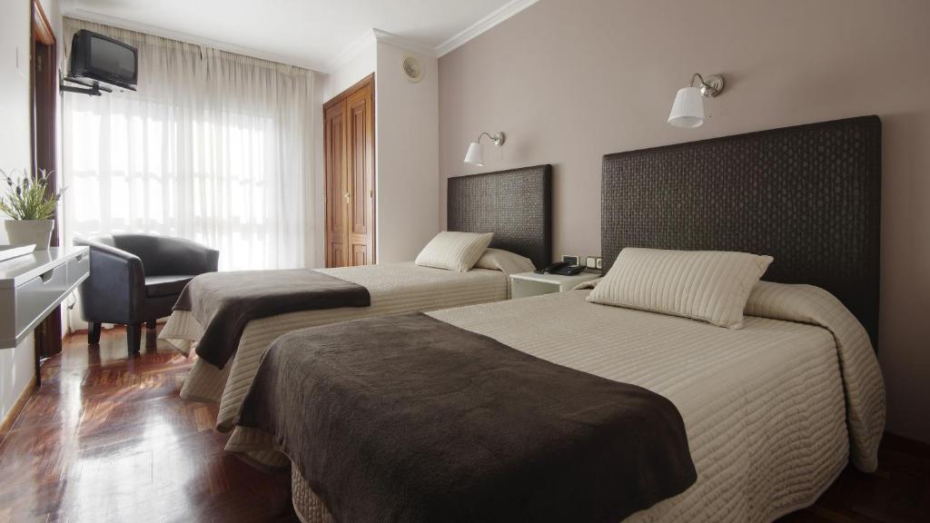 a hotel room with two beds and a desk at Hotel City Express Comercio in Pontevedra