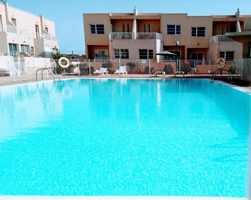 une grande piscine bleue en face d'un bâtiment dans l'établissement Litha House, 3 Bed Holiday Home set Over 3 Floors 2 Mins From Beach and all Amenities, à Caleta de Fuste