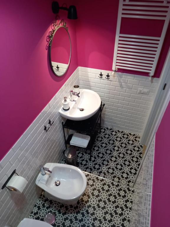 W łazience znajduje się biała umywalka i różowa ściana. w obiekcie B&B Stella Scugnizza w mieście Neapol