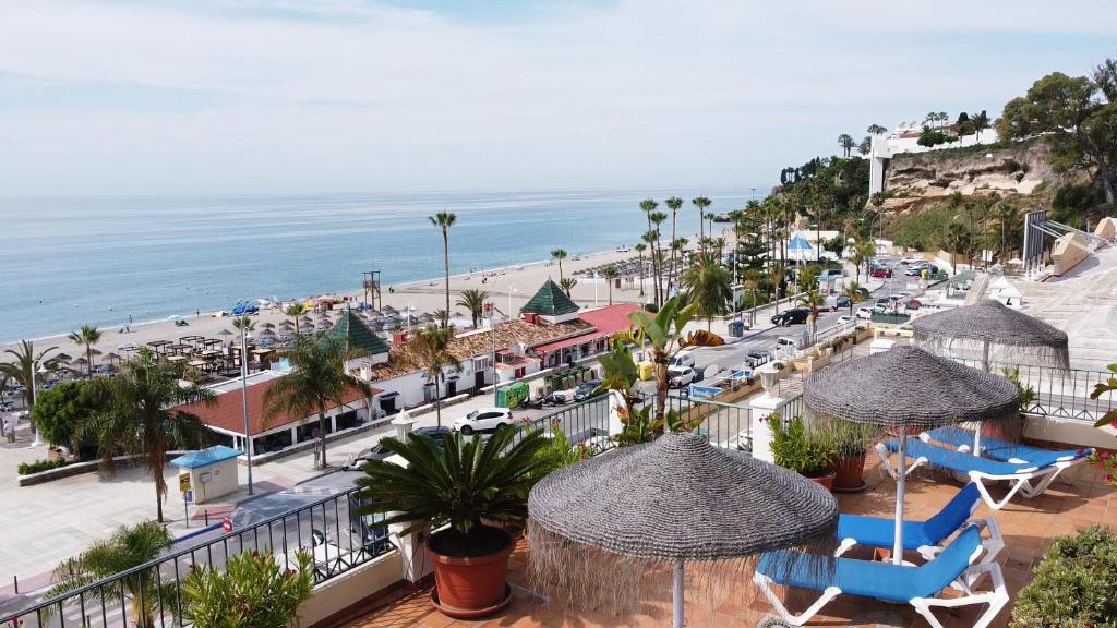 a balcony with chairs and umbrellas and a beach at Apartamentos HC Burriana Playa in Nerja