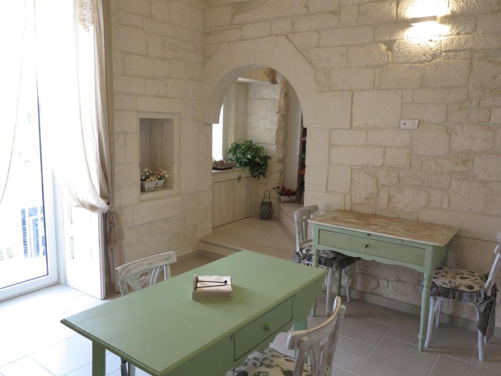 a room with two green tables and a stone wall at Casa Nonna Stella in Martina Franca