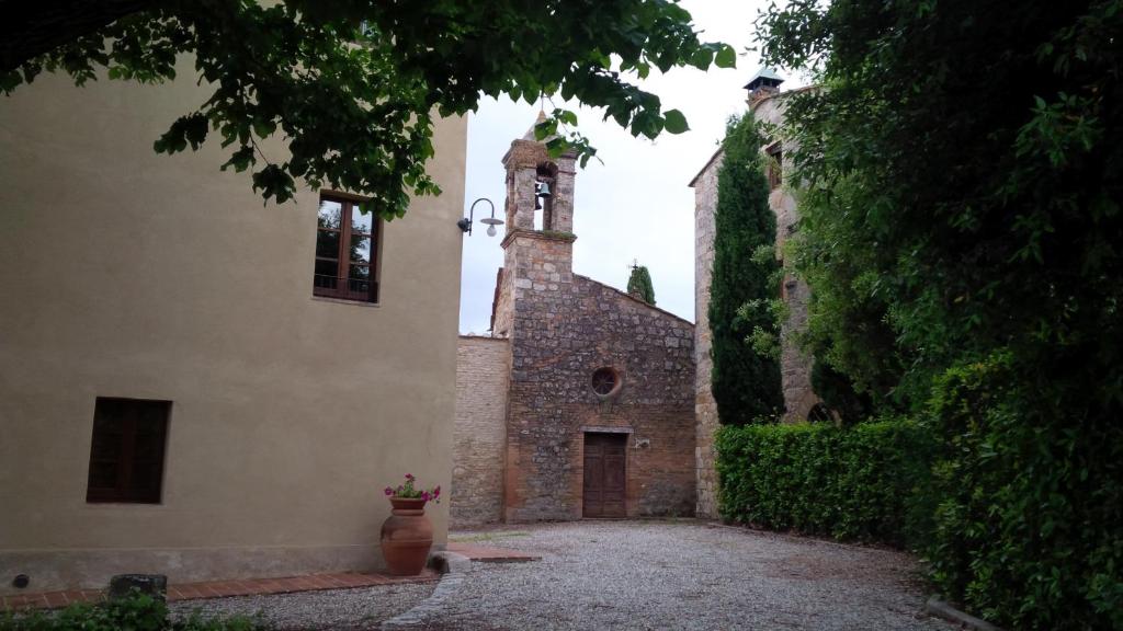 un edificio con una torre dell'orologio e un vaso in un cortile di Antico Borgo De' Frati a San Gimignano