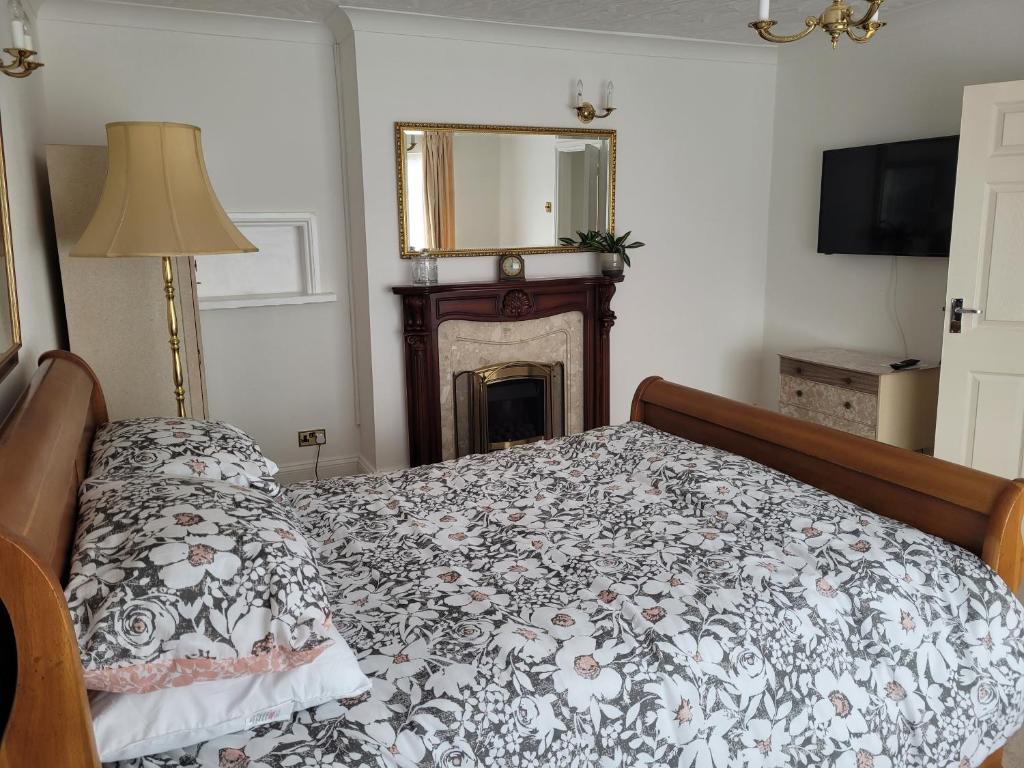 1 dormitorio con cama, chimenea y espejo en Sandy Retreat en Worle