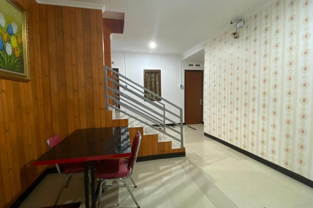 a dining room with a table and a staircase at RedDoorz Plus @ Rawamangun in Jakarta