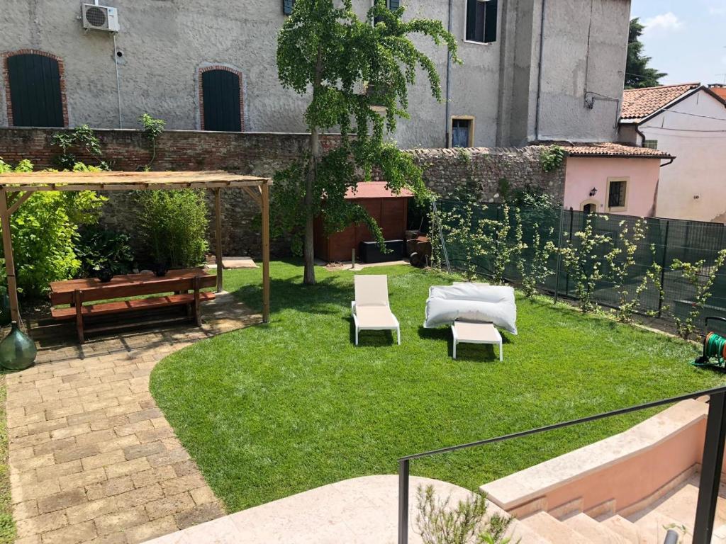 einen Hinterhof mit zwei Stühlen und einer Matratze auf dem Rasen in der Unterkunft Corte Angelini in Castelnuovo del Garda
