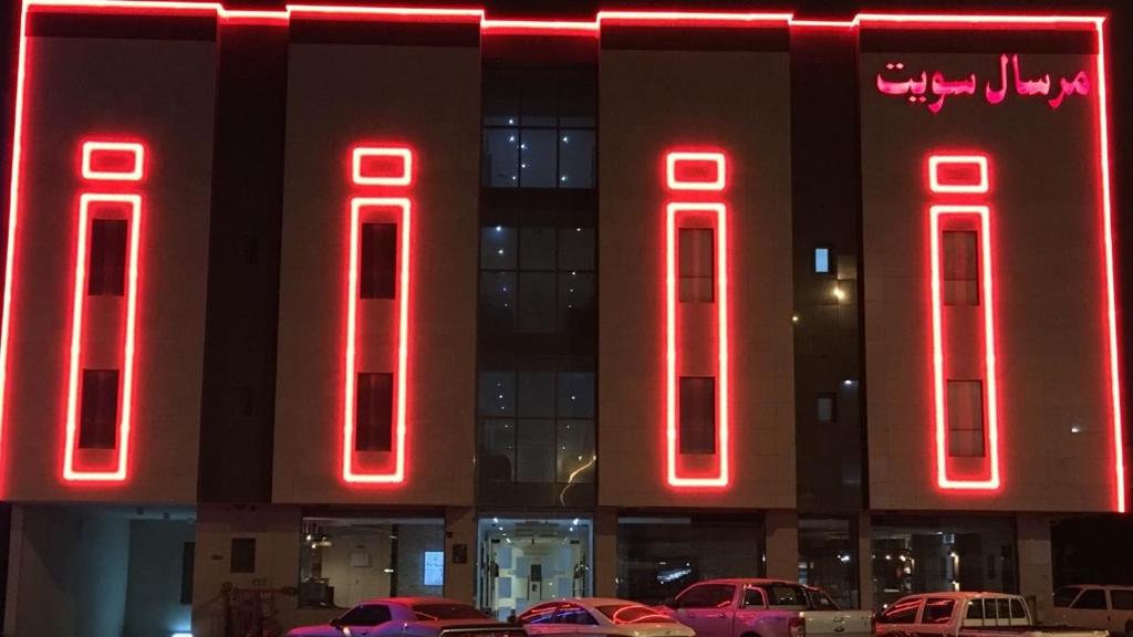 un edificio con letreros de neón rojo delante de él en مقصورة مرسال سويت, en Riad