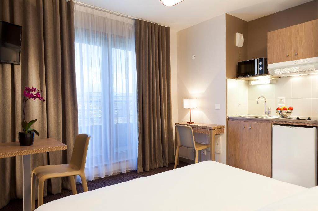 een hotelkamer met een bed en een keuken bij Nehô Suites Porte de Genève in Annemasse