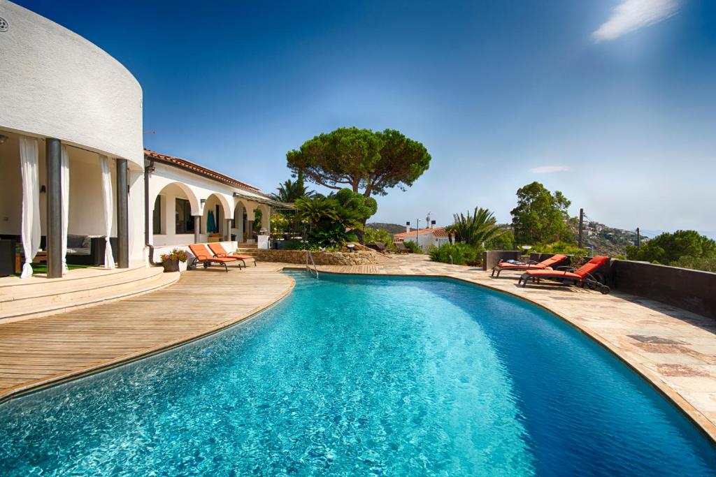 una piscina junto a una casa con terraza de madera en Casa de l’Albada en Rosas