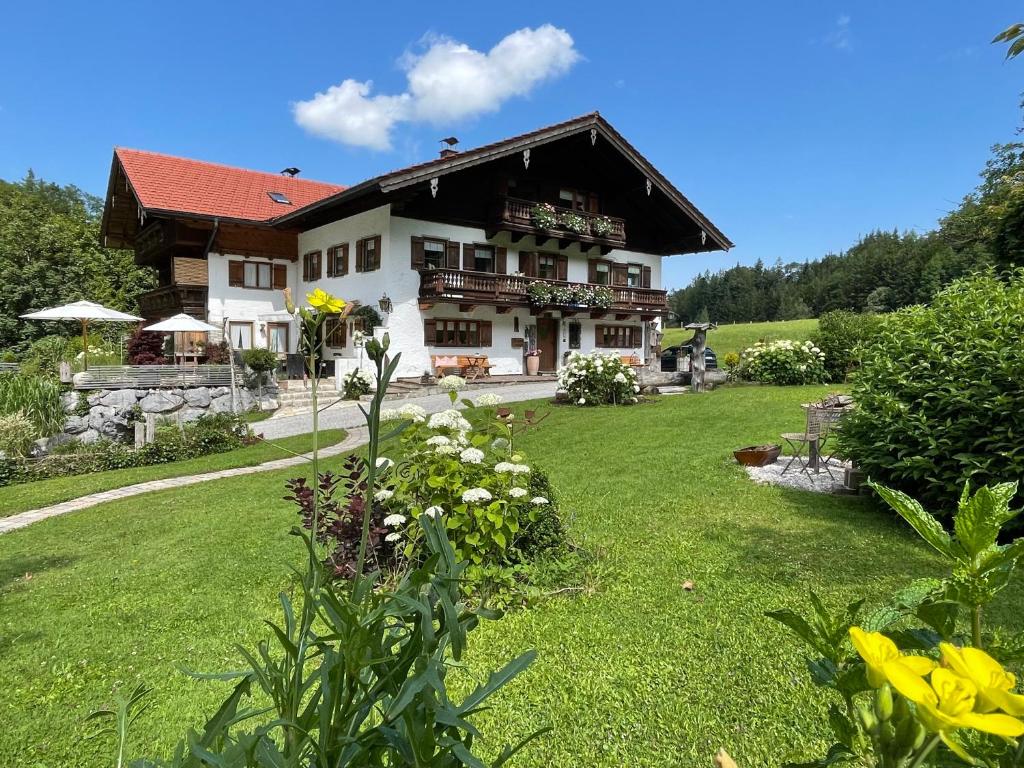 une grande maison avec une cour verdoyante ornée de fleurs dans l'établissement Kienberghof, à Inzell