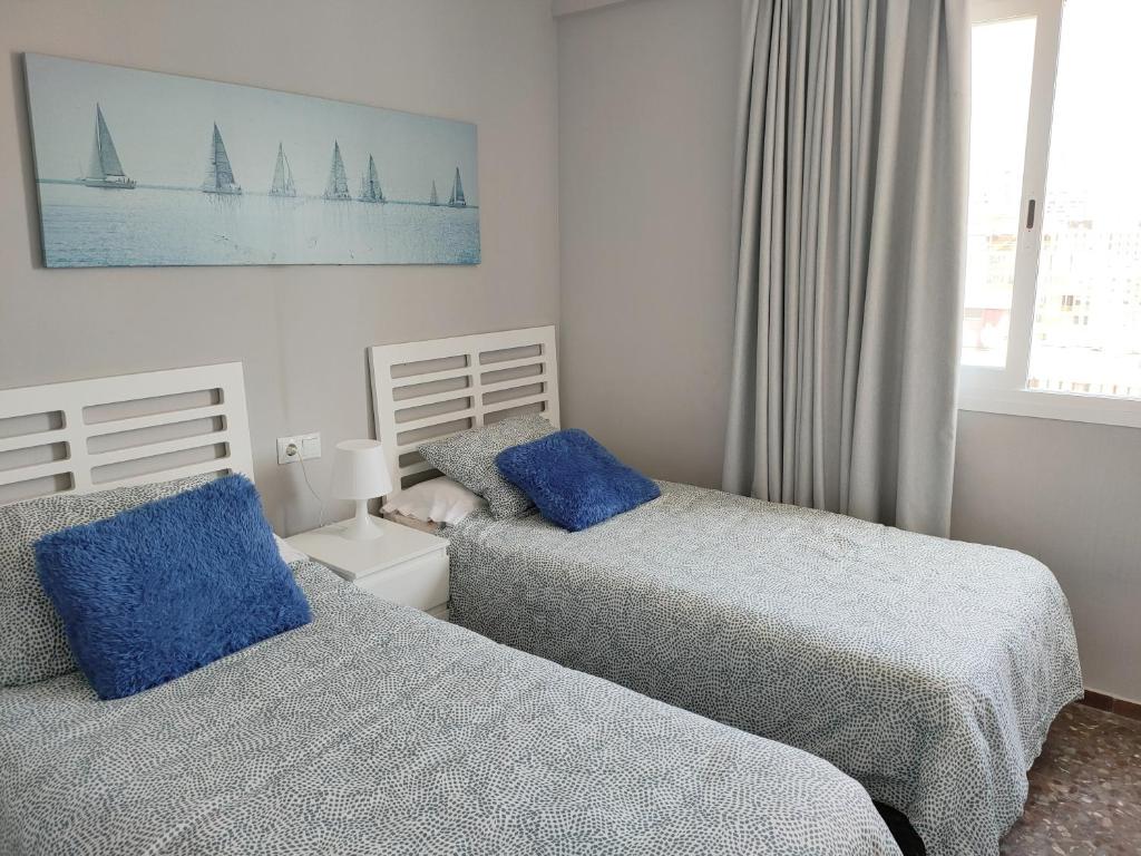 sypialnia z dwoma łóżkami i niebieskimi poduszkami w obiekcie Apartamento Veracruz - Primera Linea de Playa w mieście Benidorm