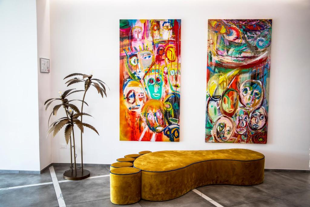 a couch in front of three paintings on a wall at One Design Hotel in Rimini