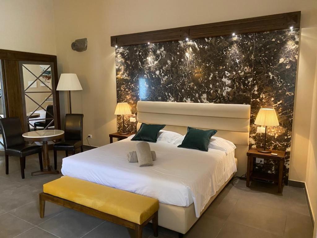 Un dormitorio con una gran cama blanca y una mesa en Firriato Hospitality Cavanera Etnea Resort & Wine Experience, en Castiglione di Sicilia