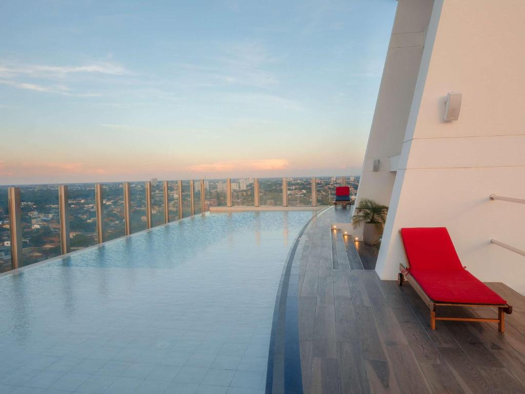 a swimming pool on top of a building with a red chair at Swissotel Santa Cruz de La Sierra in Santa Cruz de la Sierra