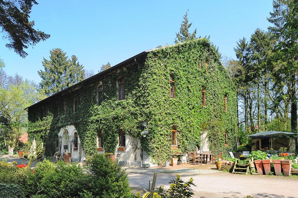 a building covered in ivy with tables and chairs at Pension Altes Posthaus in Dangast