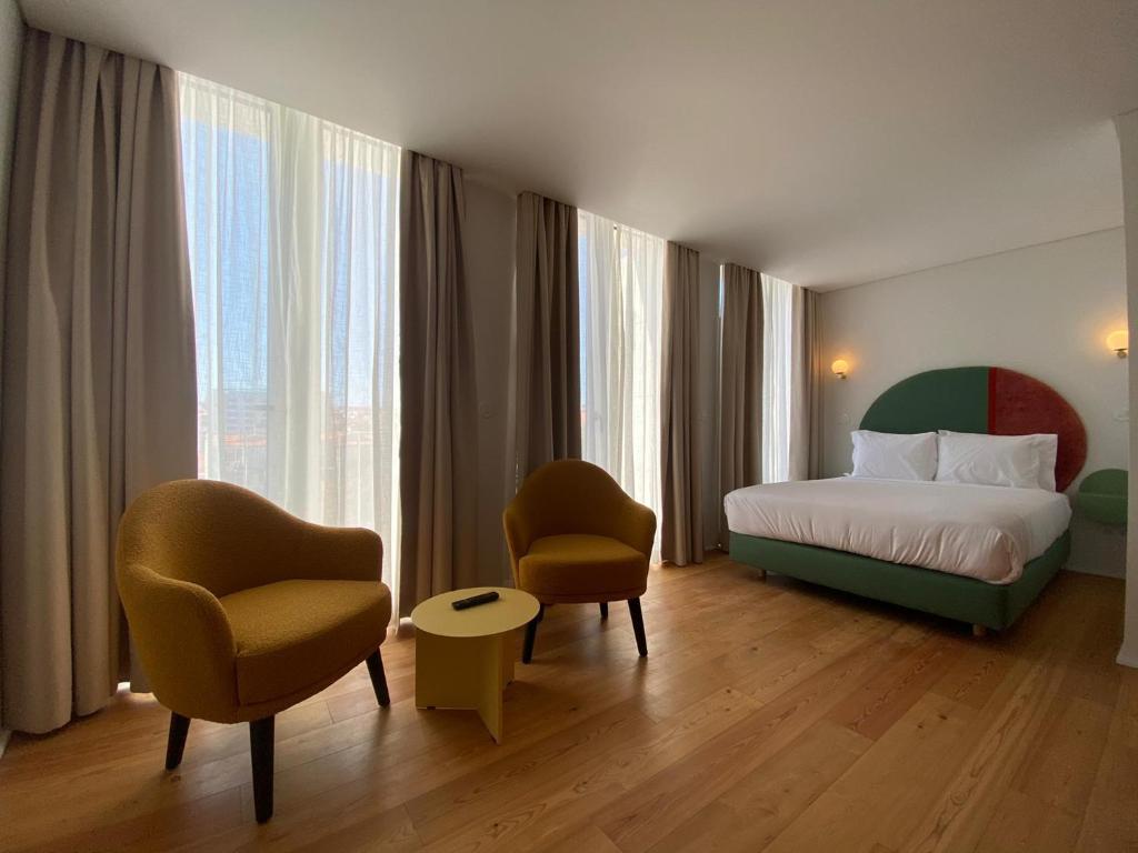 um quarto de hotel com uma cama e duas cadeiras em Lisbon Serviced Apartments - Estrela em Lisboa