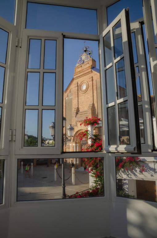 un bâtiment avec une tour d'horloge à travers une fenêtre dans l'établissement Hostal Atalaya, à Benalup-Casas Viejas
