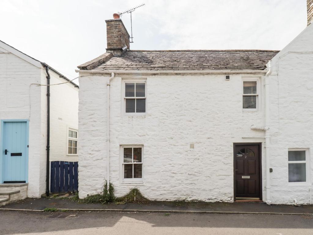 uma velha casa de tijolos brancos com uma porta preta em 2 Burnside Place em Kirkcudbright
