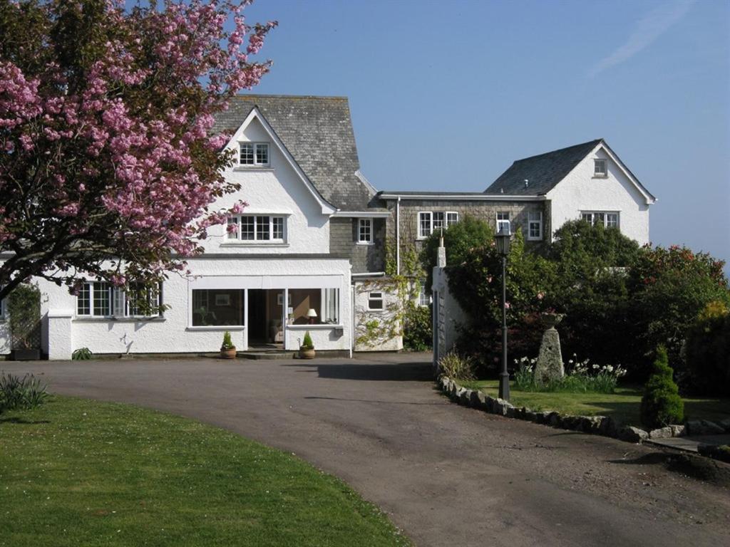 a white house with a flowering tree in front of it at Trelawne Hotel in Falmouth