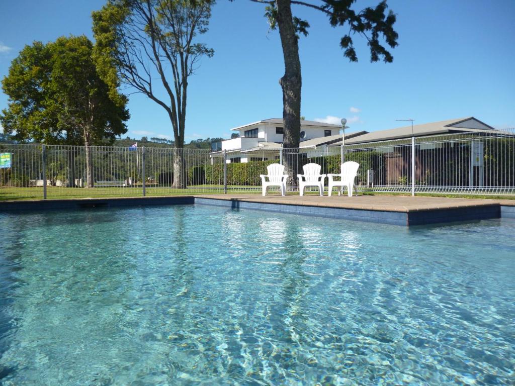 two white chairs sitting next to a swimming pool at Harbourside Holiday Park in Whitianga