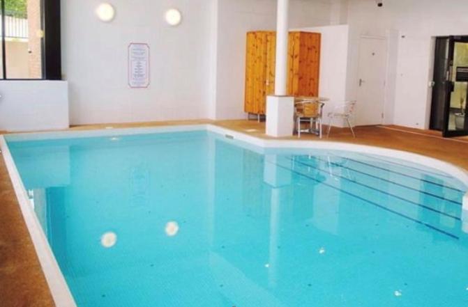 a large blue swimming pool in a building at Apartment with Swimming Pool in Tenby