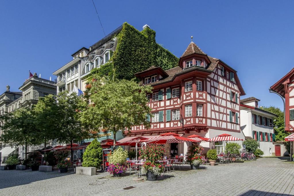 un grand bâtiment avec des parasols rouges devant lui dans l'établissement Hotel Rebstock, à Lucerne