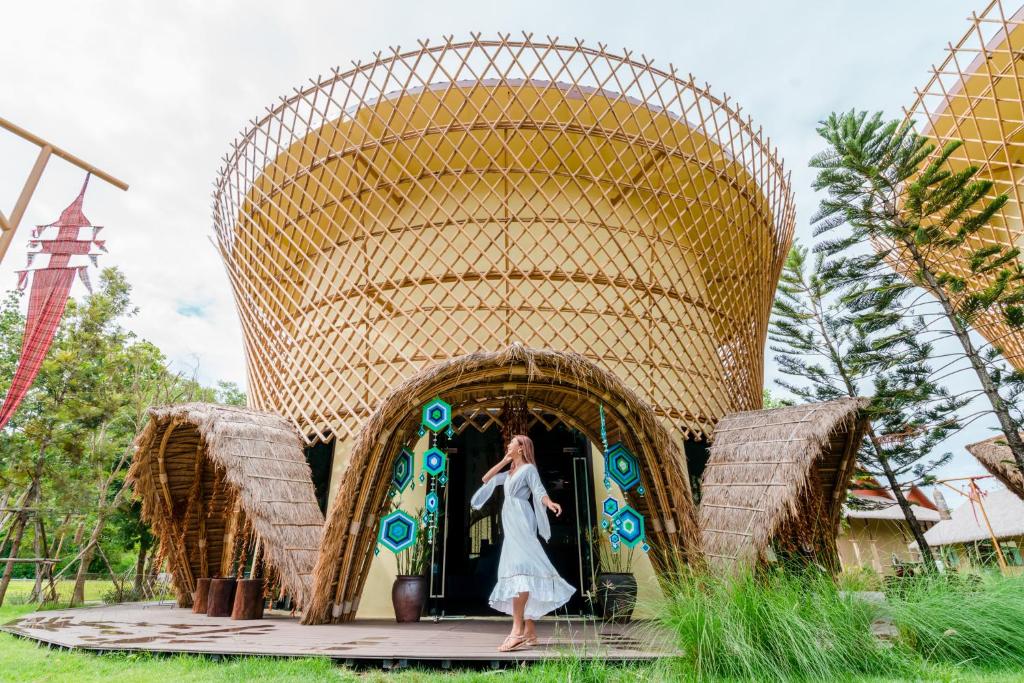 een vrouw in een jurk die voor een ingang van een gebouw staat bij Recall Isaan Isan Concept at Khaoyai SHA Extra Plus in Mu Si