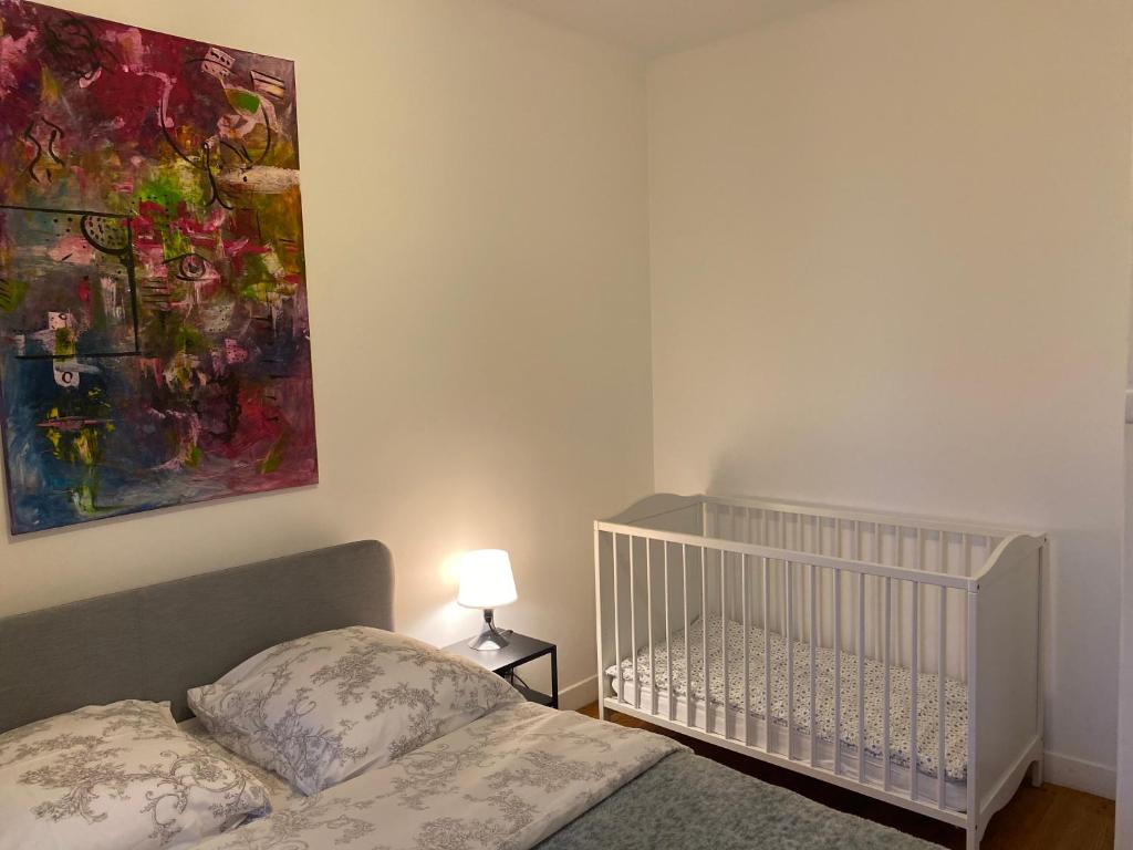 - une chambre avec un lit bébé et un tableau mural dans l'établissement Maison chaleureuse avec un grand jardin, à La Bonneville