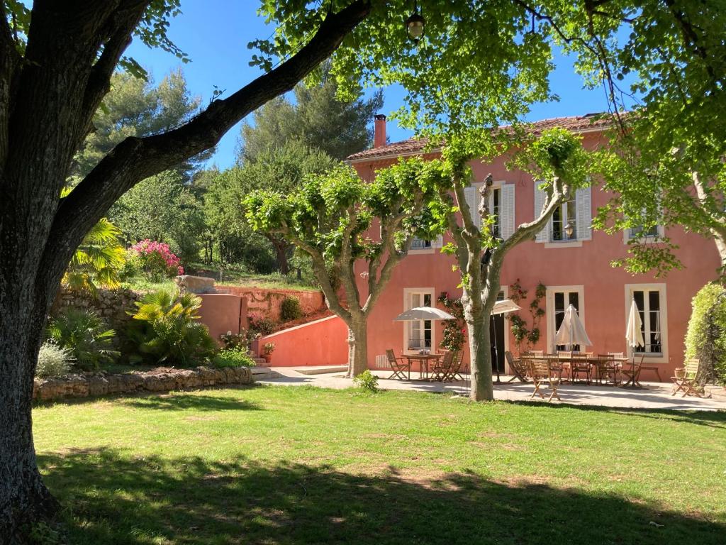 une grande maison rose avec des arbres devant elle dans l'établissement La Féraude - Pays d'Aix en Provence, à Gardanne