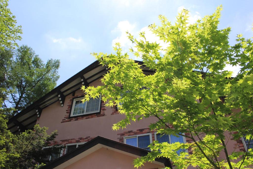 un árbol delante de una casa en Pension Candytuft, en Karuizawa