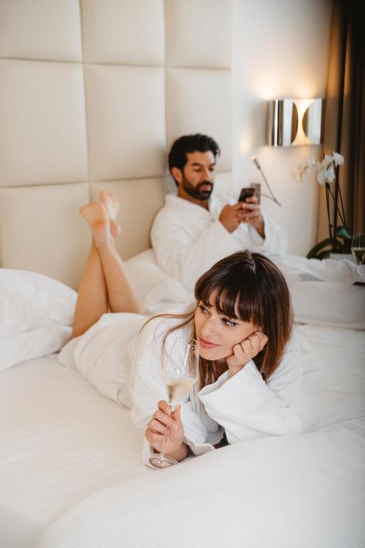 a woman laying on a bed with a man taking a picture at Jazz Hotel in Olbia