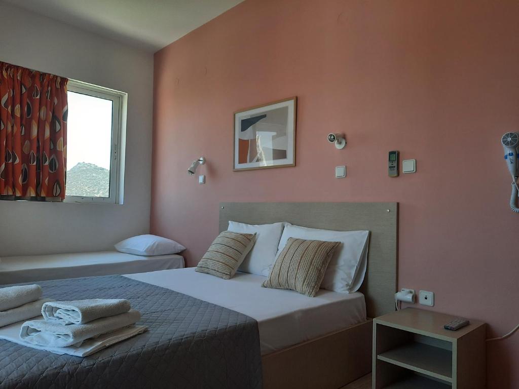 a bedroom with a bed with orange walls and a window at Ntemos Apartments in Tolo