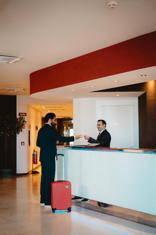 two men standing at a counter in an airport at Jazz Hotel in Olbia