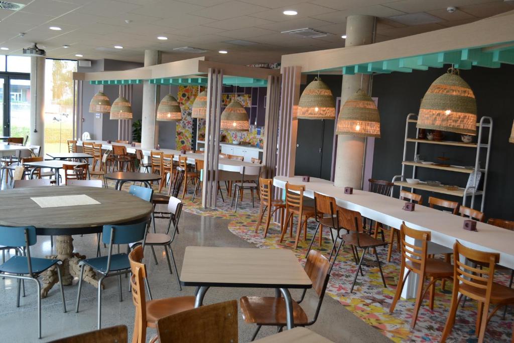 greet Hotel Rennes Pace في Pacé: مطعم فيه طاولات وكراسي في الغرفة