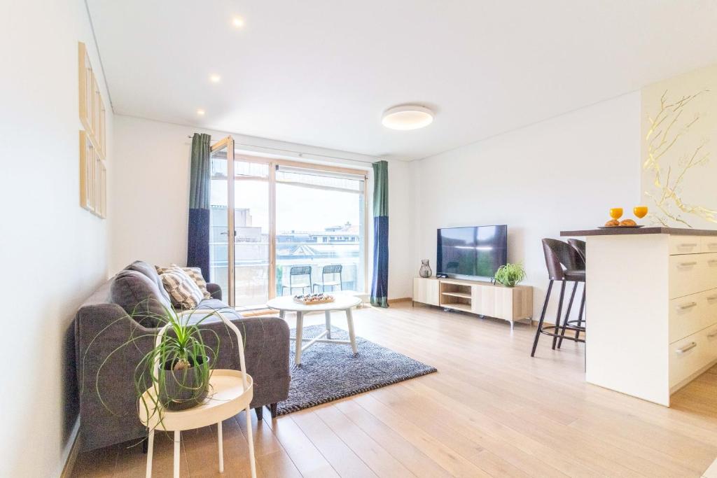 a living room with a couch and a table at Sunny Center Apt, Covered Parking, Balcony & Self Check-in in Kaunas