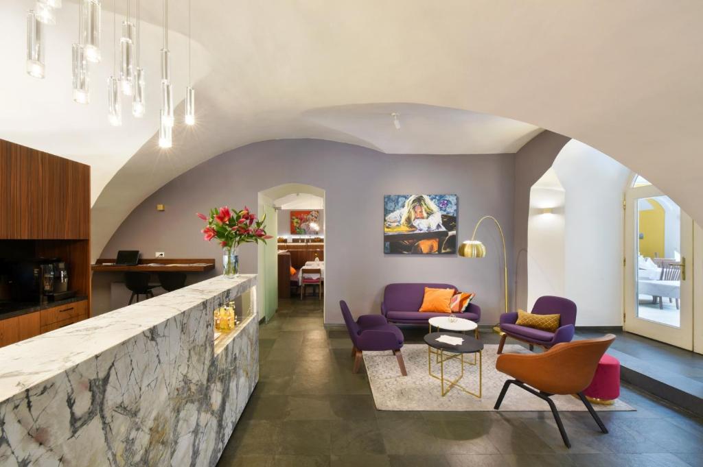 a living room with purple chairs and a stone wall at BoutiqueHotel Dom - Rooms & Suites in Graz