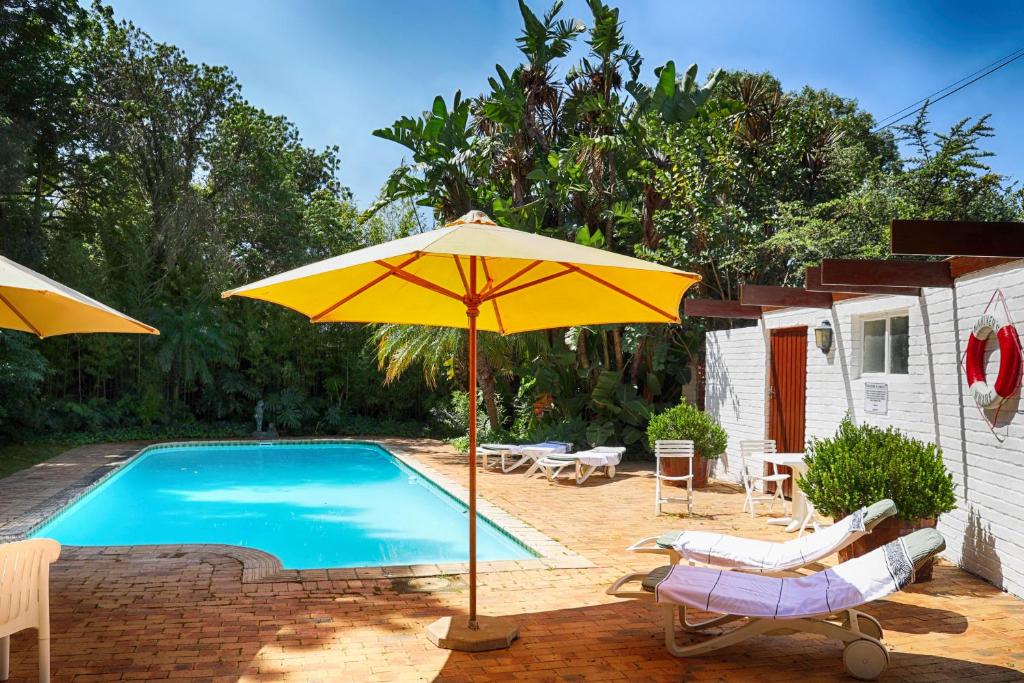 a yellow umbrella next to a swimming pool at Auberge de Courtrai in Paarl