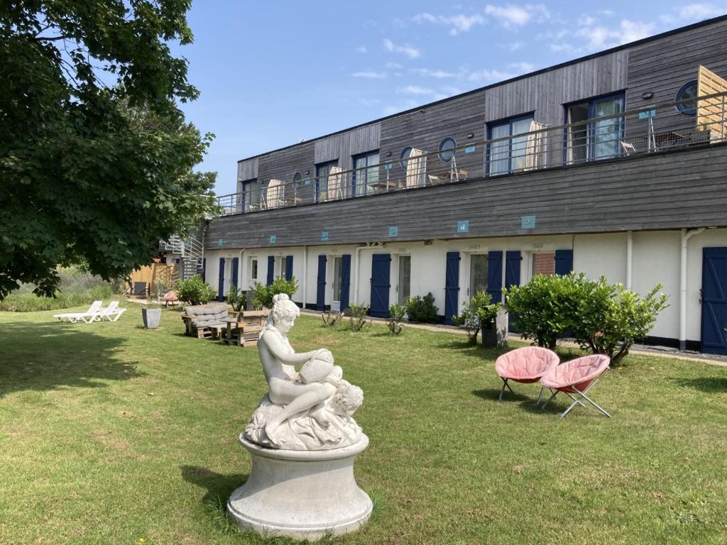 Une statue dans l'herbe devant un bâtiment dans l'établissement Hôtel Des Argousiers, à Ambleteuse