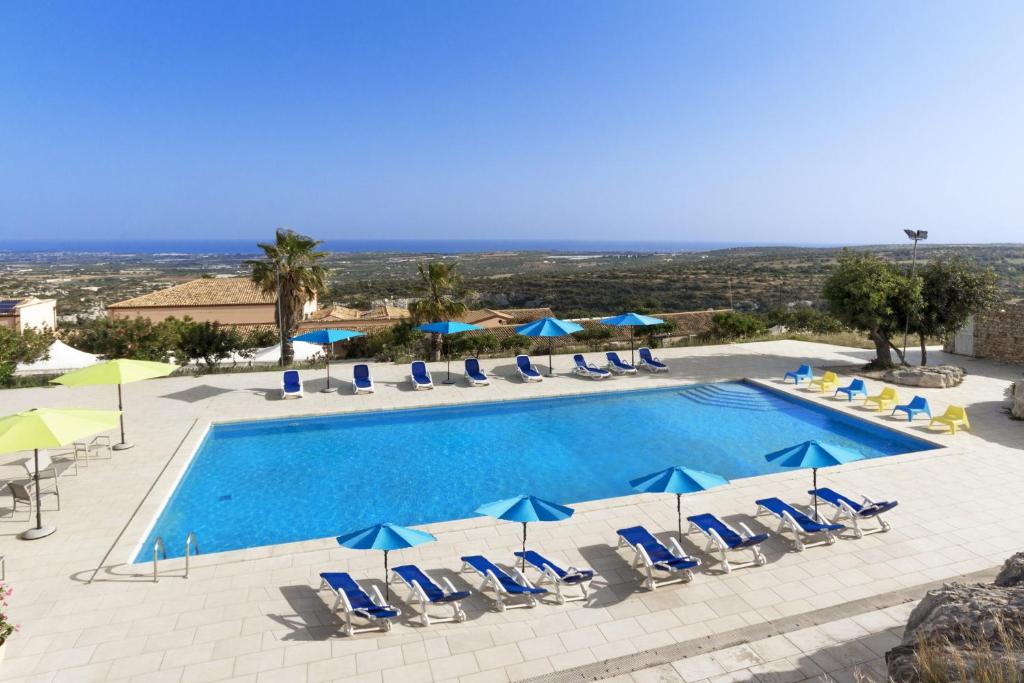 ein großer Pool mit Stühlen und Sonnenschirmen in der Unterkunft Villa Principe Di Belmonte in Ispica