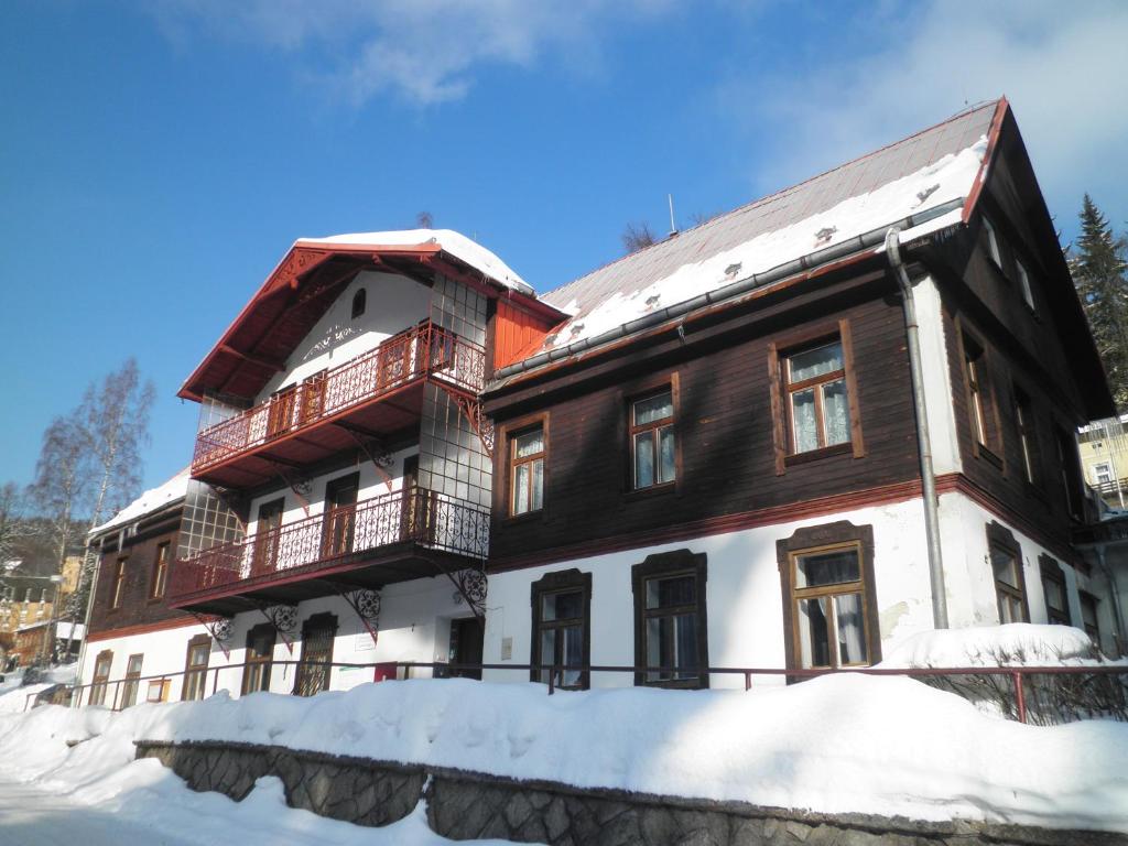 a large wooden building with snow on the ground at Penzion Betlém in Janske Lazne