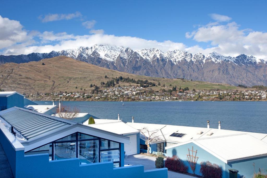 uma casa com vista para um lago e montanhas em Apartments at Spinnaker Bay em Queenstown