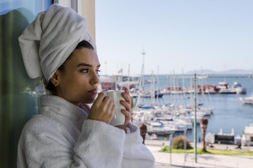 a woman in a towel holding a cup of coffee at Hotel Aristeo in Cagliari