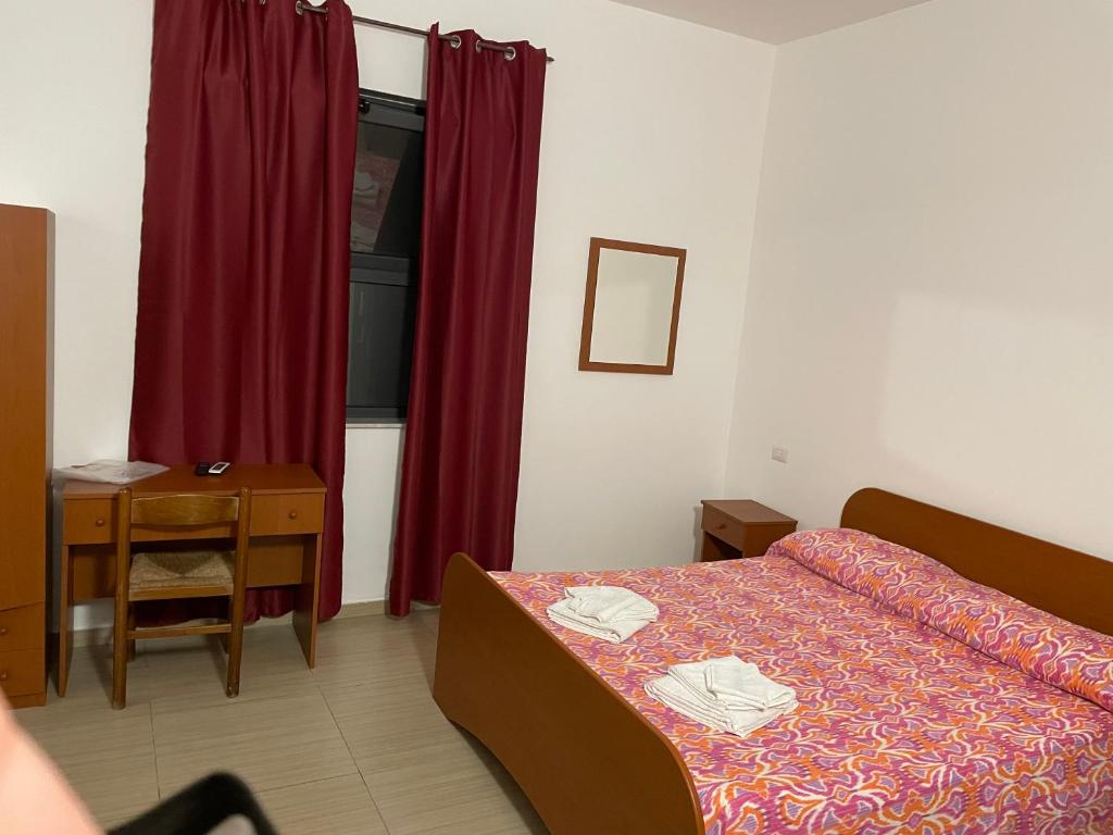 a bedroom with a bed and a table and a red curtain at B&B Cuciti in Milazzo