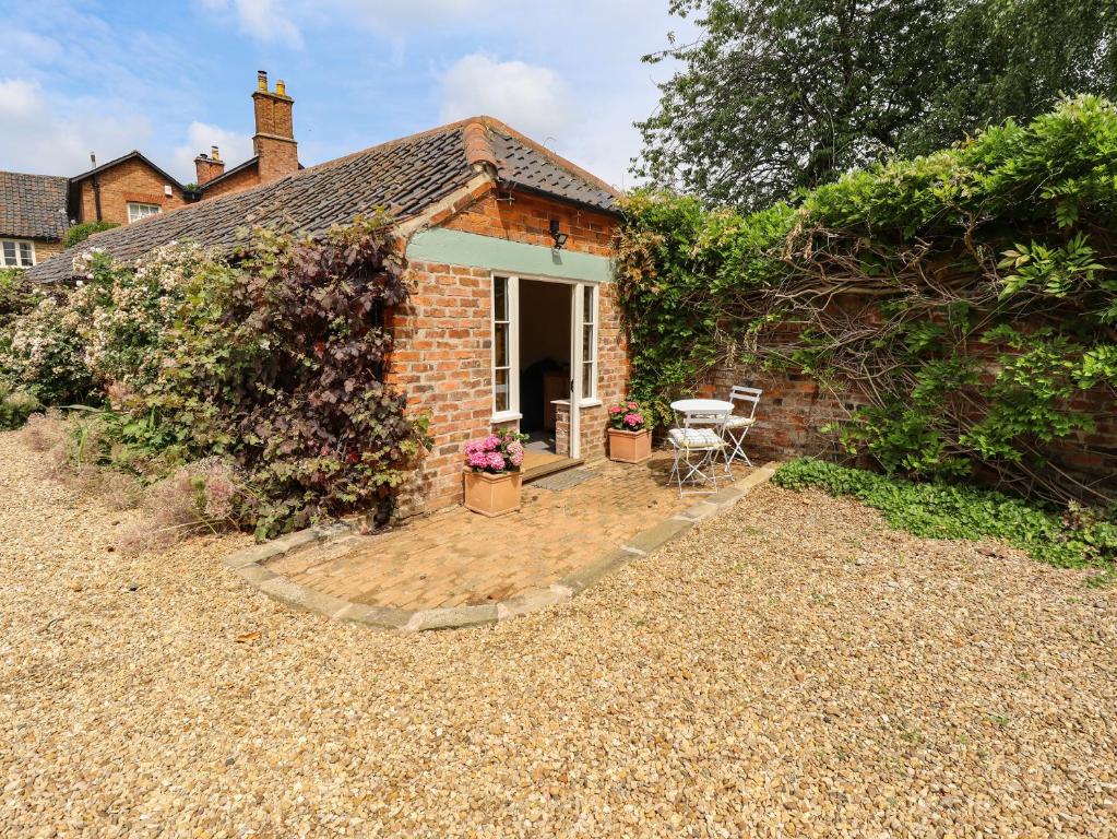 a brick cottage with a patio in the yard at The Old Mower Shed in Grantham