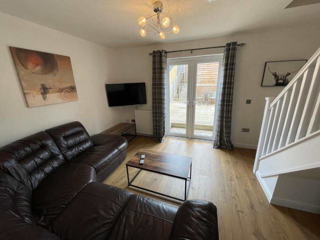 a living room with a leather couch and a tv at Gorsebank Mews in Inverness