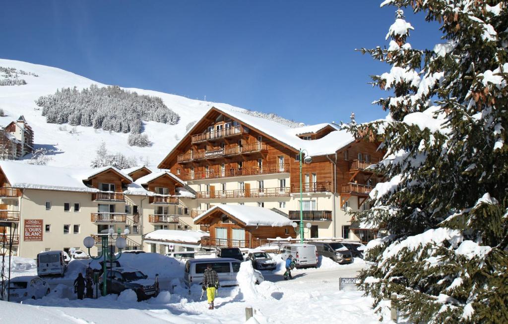 un pavillon de ski dans la neige avec des voitures garées dans l'établissement Résidence Odalys L'Ours Blanc, à Les Deux Alpes