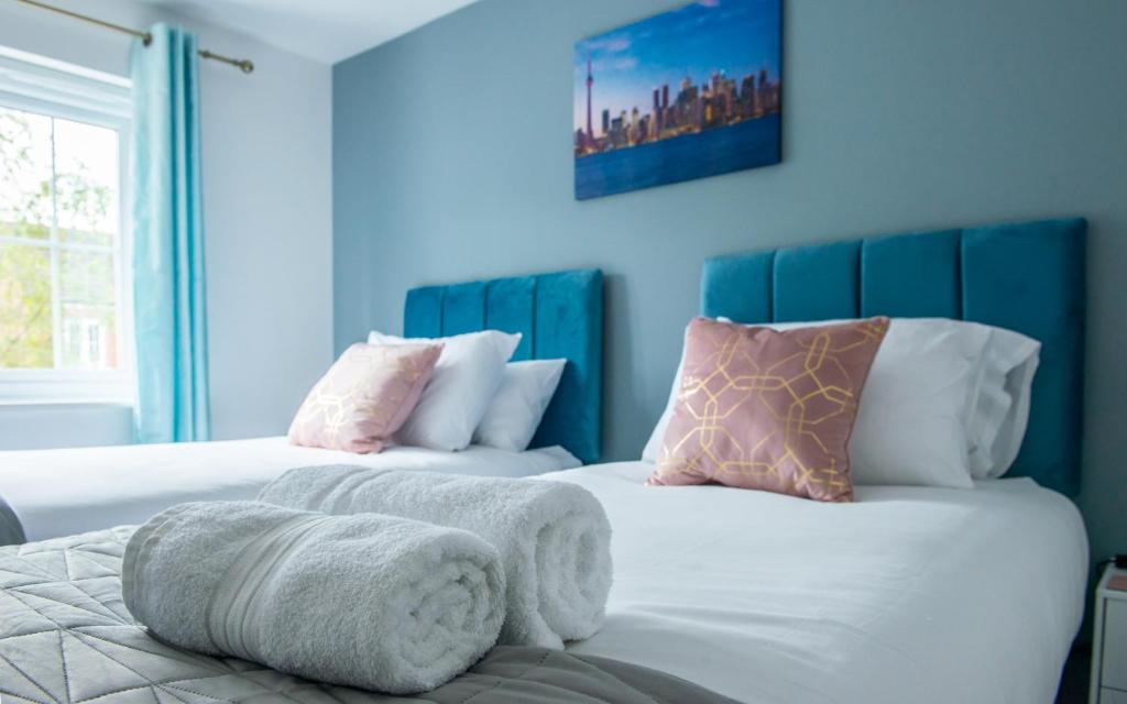twee bedden in een kamer met blauwe muren bij RATED 'EXCEPTIONAL' 3 BEDROOM HOUSE, SLEEPS 6, FREE PARKING, Near NEC in Tile Hill