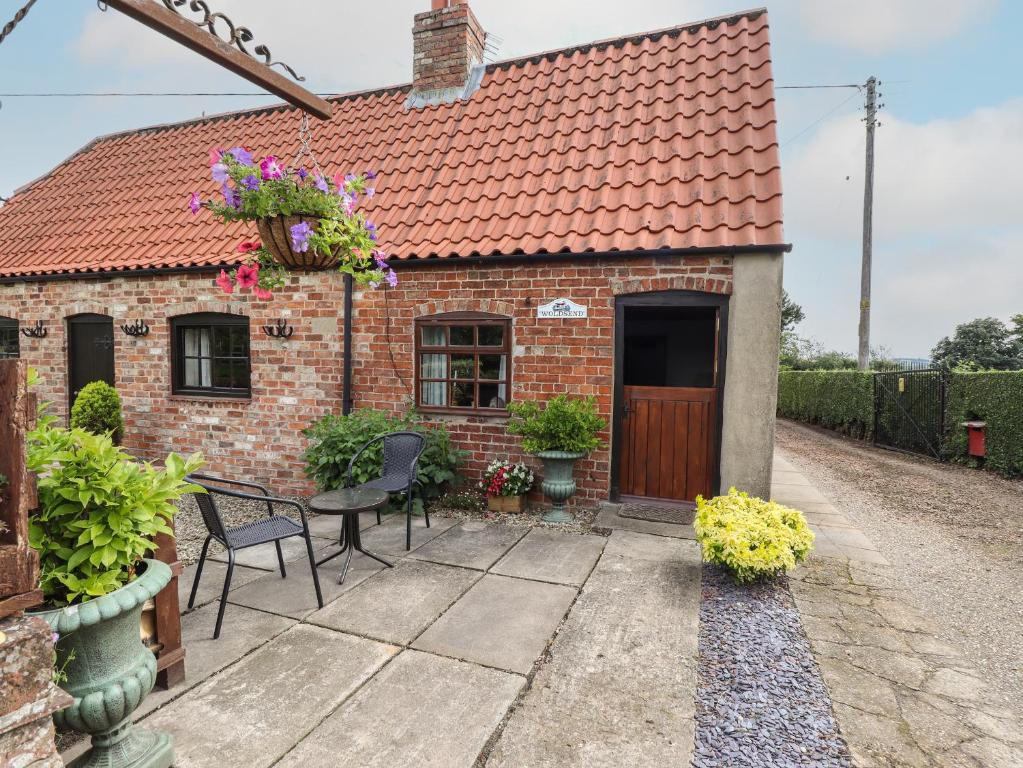 uma casa de tijolos com mesa e cadeiras em Woldsend Cottage em Horncastle