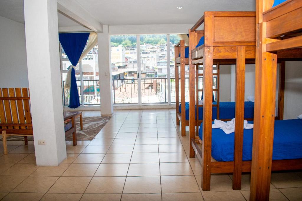 a room with three bunk beds and a balcony at Hostal Corazón de San Pedro in San Pedro La Laguna
